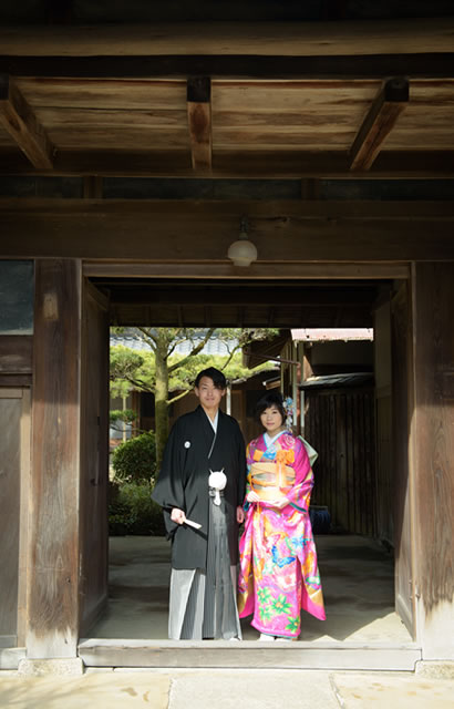 花嫁と花婿が木造建築物の門の下で撮影された画像