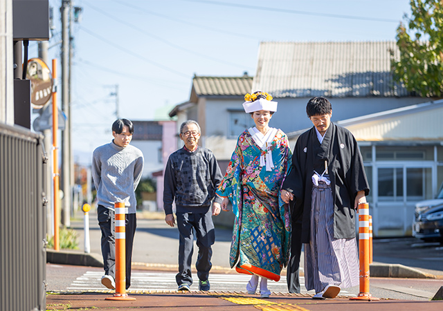 田園風景の中のウエディングドレスとタキシードの二人の画像